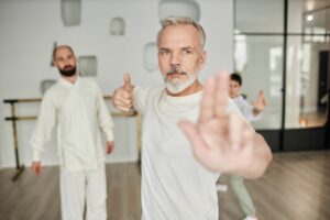 homme pratiquant mouvement de Qi Gong et professeur à l'arrière